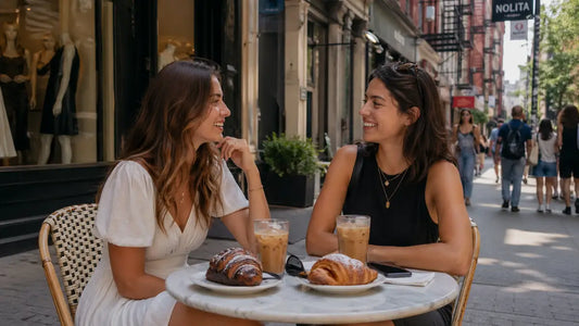 Two friends enjoying iced coffee and pastries at an outdoor cafe in Nolita during summer