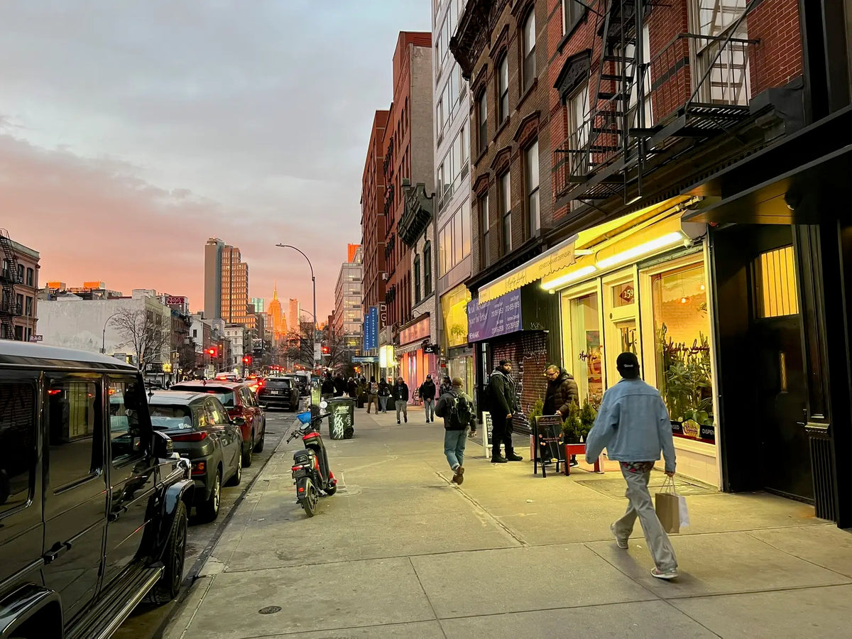 Mighty Lucky’s lit storefront at 259 Bowery at dusk, with the street running north toward the Empire State Building