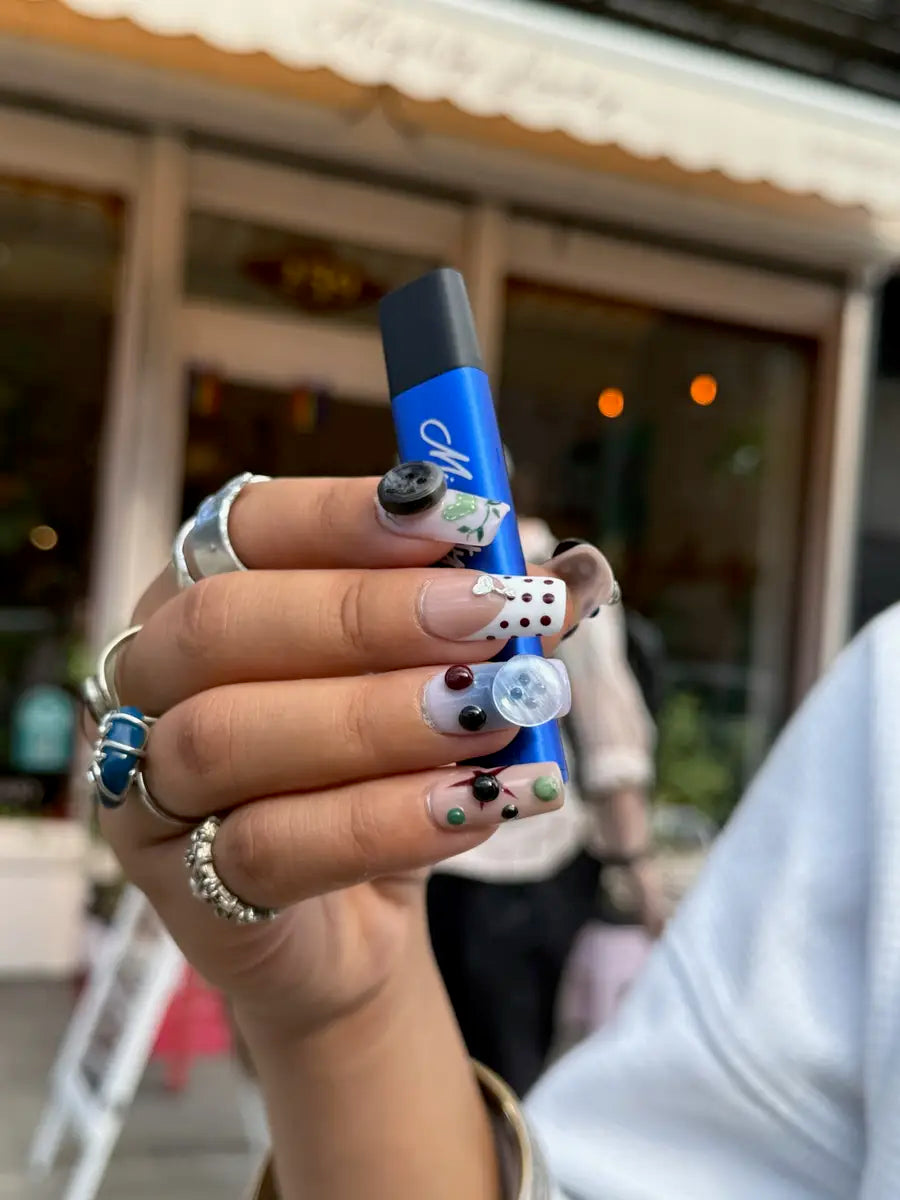 Hand holding a Mighty Lucky cannabis vape pen outside the dispensary storefront on Bowery, New York